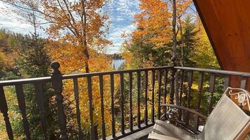 A balcony with a chair, surrounded by autumn foliage.