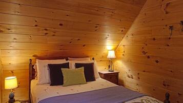 A wooden-paneled bedroom with a bed, two bedside tables, and lamps.