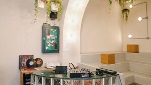 Zona de recepción con mostrador curvo, tablón de anuncios y plantas colgantes.
