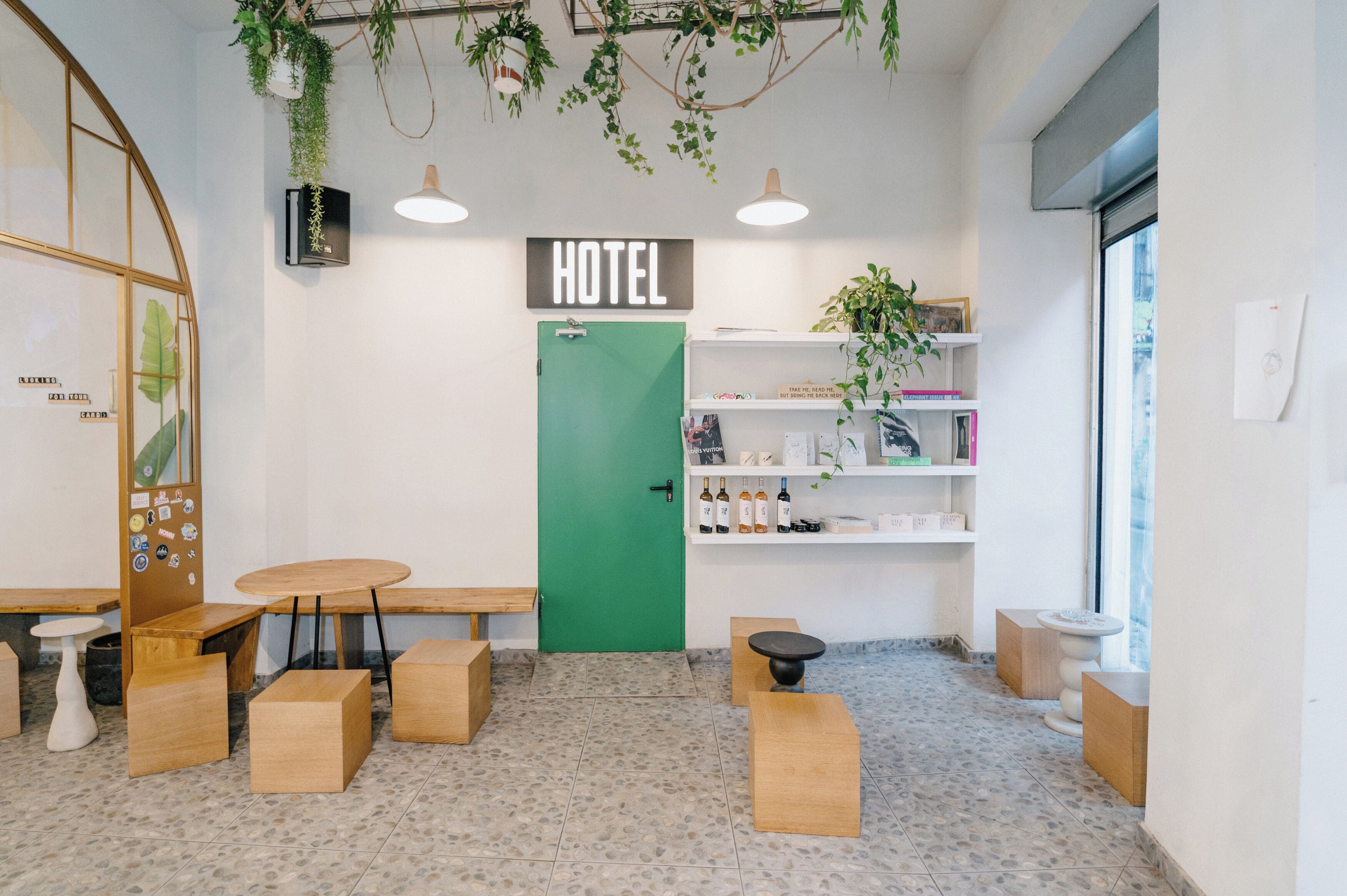 Un hall d’accueil d’hôtel avec une porte verte, des meubles en bois et une enseigne indiquant « HÔTEL ».