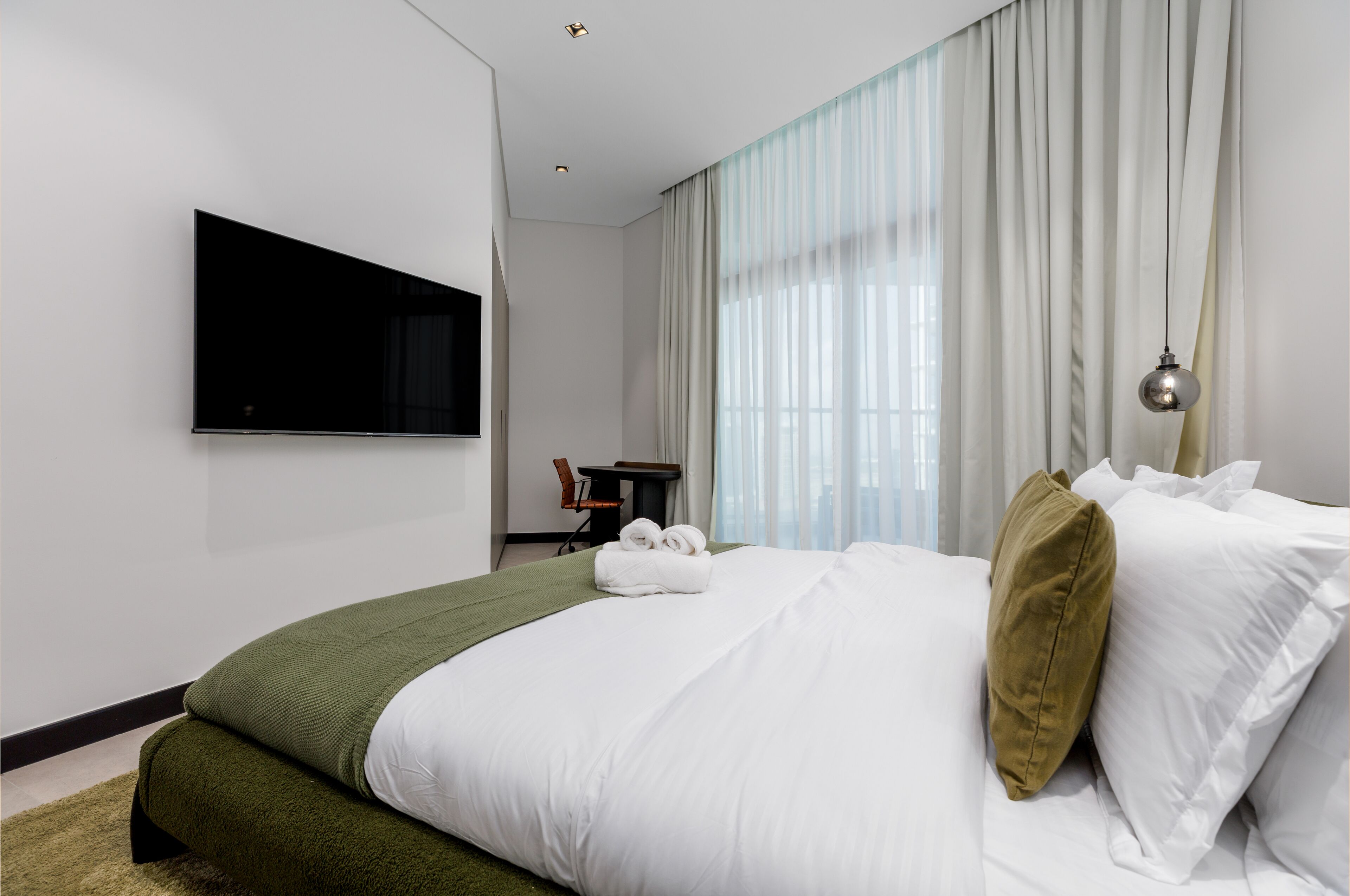 Camera d'albergo moderna con un letto grande, una TV a schermo piatto montata a parete e una scrivania con una sedia.