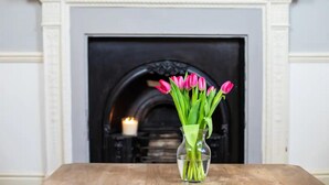 A vase with pink tulips on a wooden table in front of a fireplace. - Stunning Georgian Spacious Apartment Central Bath (Bath)