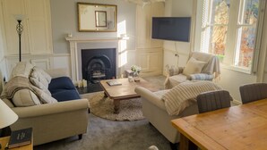 A living room with a fireplace, a television, and a view of the outside. - Stunning Georgian Spacious Apartment Central Bath (Bath)