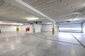 Eine leere Parkgarage mit Betonböden und -wänden, gelb-schwarz gestreiften Poller und einer Garagentür.