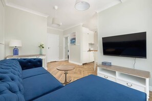 A modern living room with a large flat-screen TV, a sofa, a coffee table, and a TV stand.