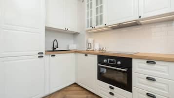 A modern kitchen with white cabinetry, a wooden countertop, and a black oven.