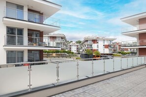 A modern apartment complex with multiple balconies, a paved walkway, and a clear sky. - Sunny Apartment | SPA and 100 m to the Beach (Rewal)