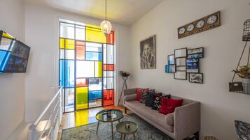 Een moderne woonkamer met een bank, salontafel en een kleurrijk glas-in-loodraam.