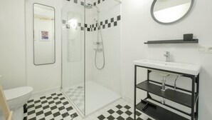 A modern bathroom with a glass-enclosed shower, a white sink with a black frame, and a checkered floor. - Boutique Duplex in Brussels - Superb Location (Molenbeek-Saint-Jean)