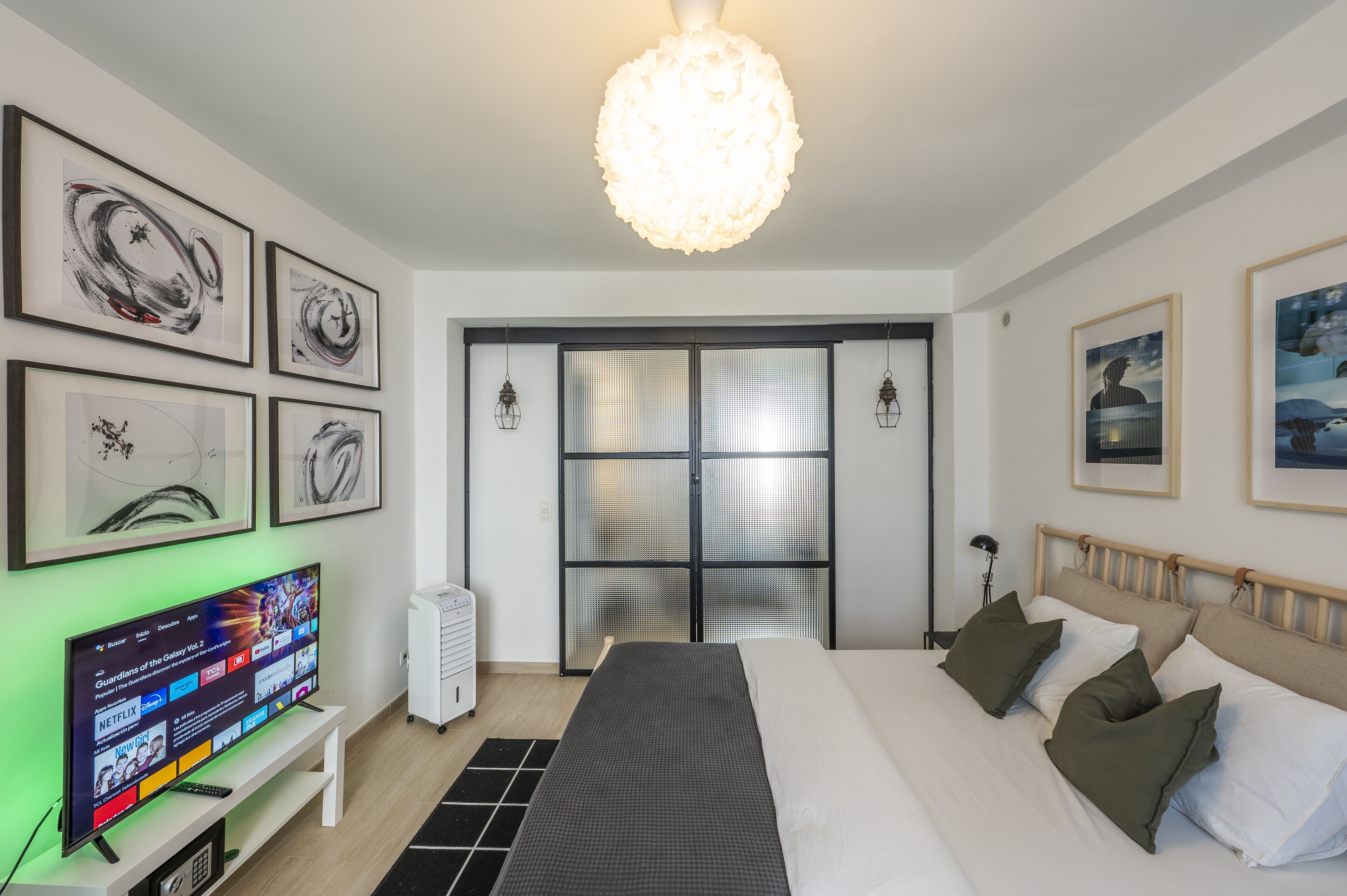Une chambre d’hôtel moderne dotée d’un grand lit, d’un téléviseur à écran plat, d’œuvres d’art aux murs et d’une grande fenêtre offrant une vue panoramique.
