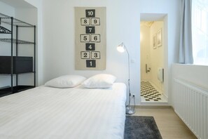 A hotel room with a bed, a number wall, a lamp, and a checkered floor.