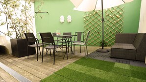 A patio area with a green wall, a table with chairs, a sofa, and a decorative wall with spherical objects. - Boutique Duplex in Brussels - Superb Location (Molenbeek-Saint-Jean)