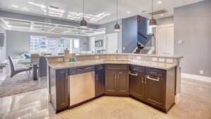A modern kitchen with dark cabinetry, granite countertops, and pendant lighting. - Cloud IX | Luxury Home In North Beach Resort (North Myrtle Beach)