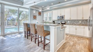 Une cuisine moderne avec des meubles blancs, un plan de travail en granit et un grand îlot central doté de tabourets.