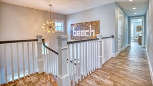 A modern interior with a wooden floor, white railing, and a ceiling light fixture.