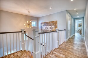 A modern interior with a wooden floor, white railing, and a ceiling light fixture.