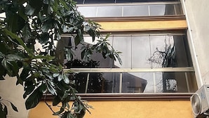 A two-story building with a yellow facade, large windows, and a visible air conditioning unit. - Yesil Hotel  (Bursa)
