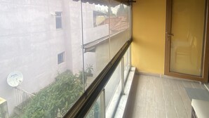 A balcony with a wooden ceiling, a glass door, and a view of buildings outside. - Yesil Hotel  (Bursa)