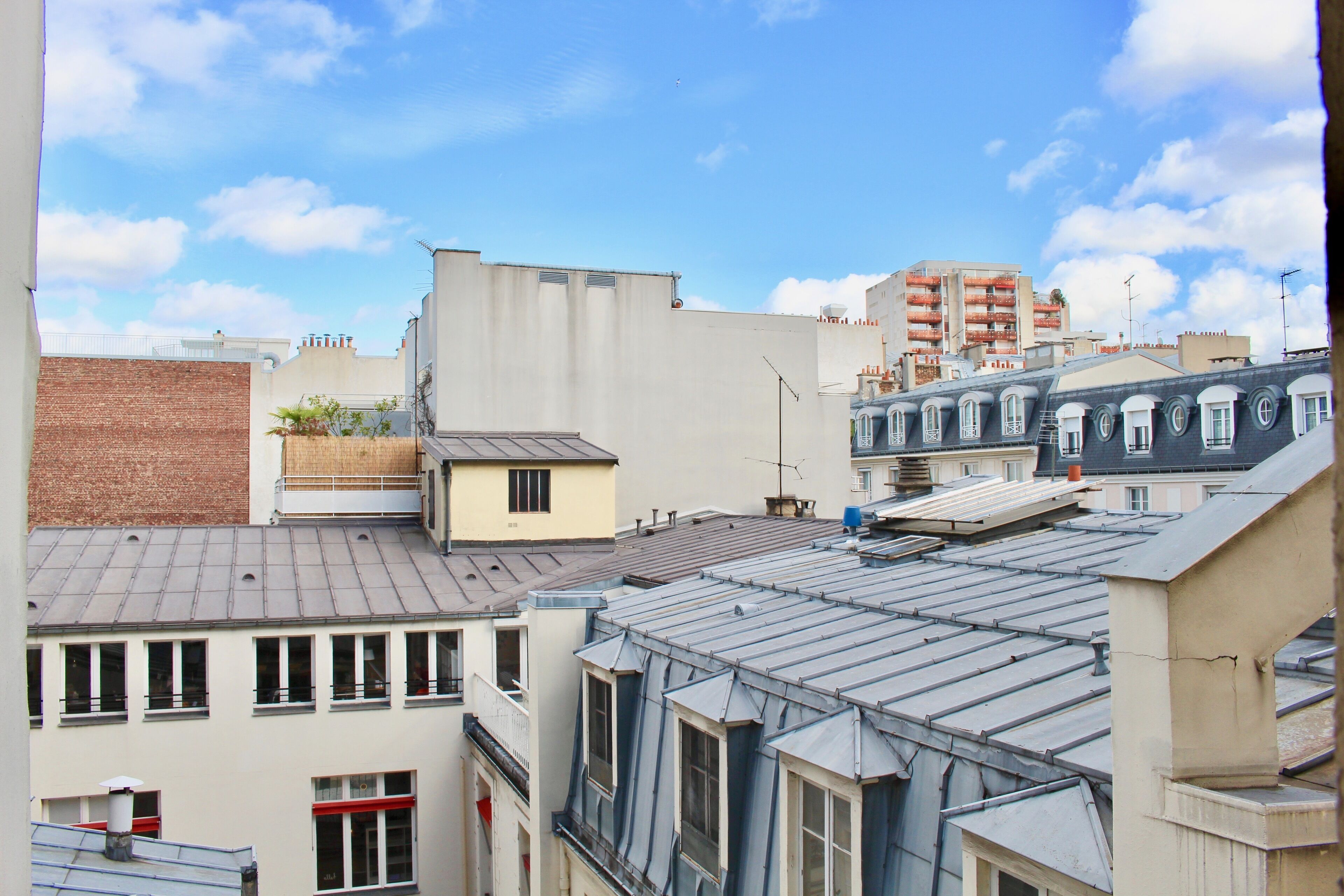 A cityscape with various buildings, including a prominent yellow building with a flat roof and a brick wall.