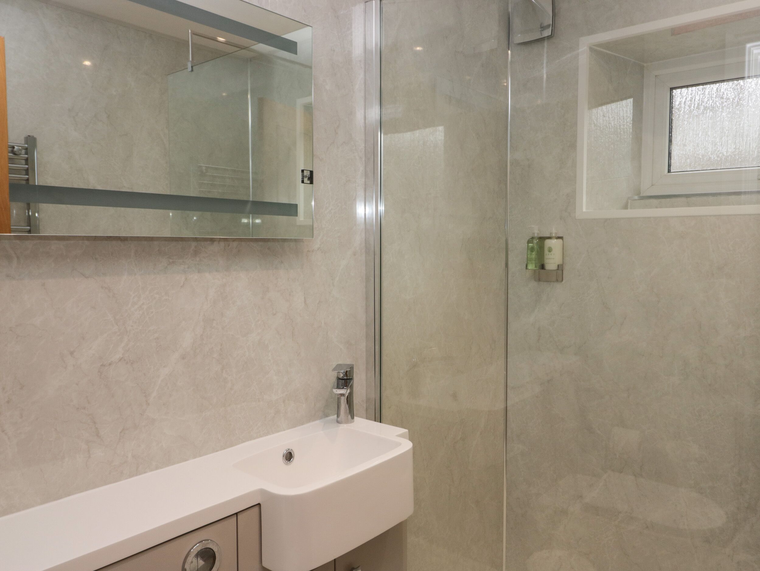 A bathroom with a white sink, a glass shower enclosure, and a mirror above the sink.