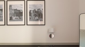 Een hotelkamer met een bed, een klein tafeltje, een wandlamp en drie ingelijste foto's aan de muur.