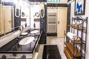 Un baño con dos lavamanos, un espejo, un perchero para toallas y una ducha.