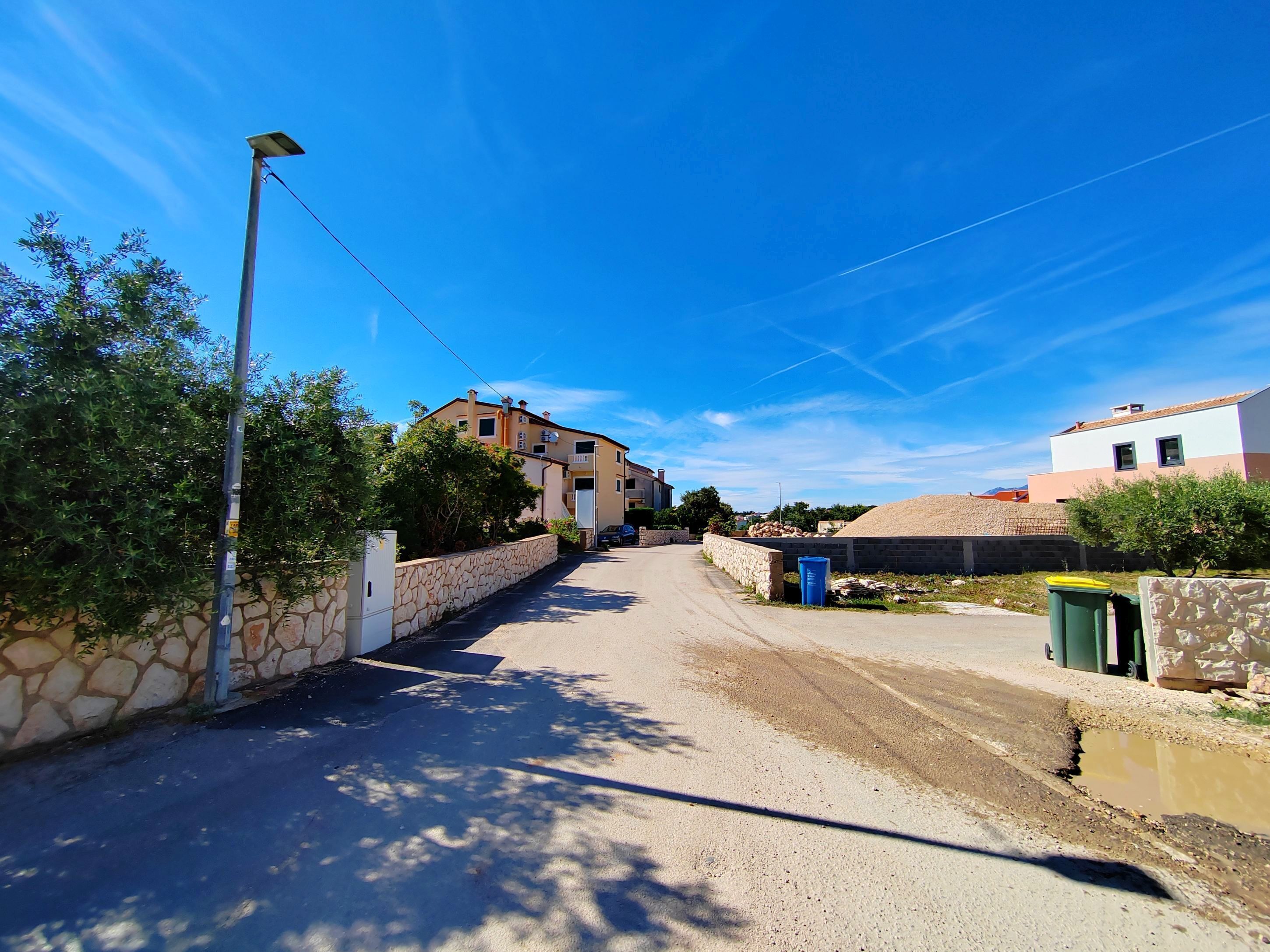 Una calle residencial con casas, un farol y un muro de piedra.