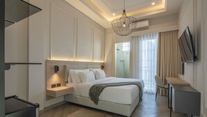 Un dormitorio moderno con una cama grande, mesitas de noche, un escritorio y un televisor.