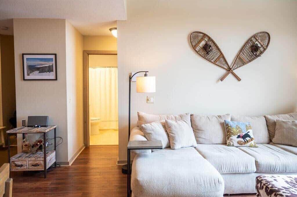A modern living room with a sofa, a small table, and a wall-mounted decorative item.
