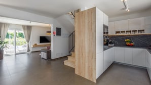 A modern kitchen with white cabinets, a wooden accent wall, and a black marble countertop.