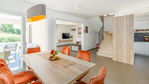 A modern dining area with a wooden table, orange chairs, and a large pendant light.