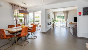 A modern dining area with a wooden table, orange chairs, and a pendant light.