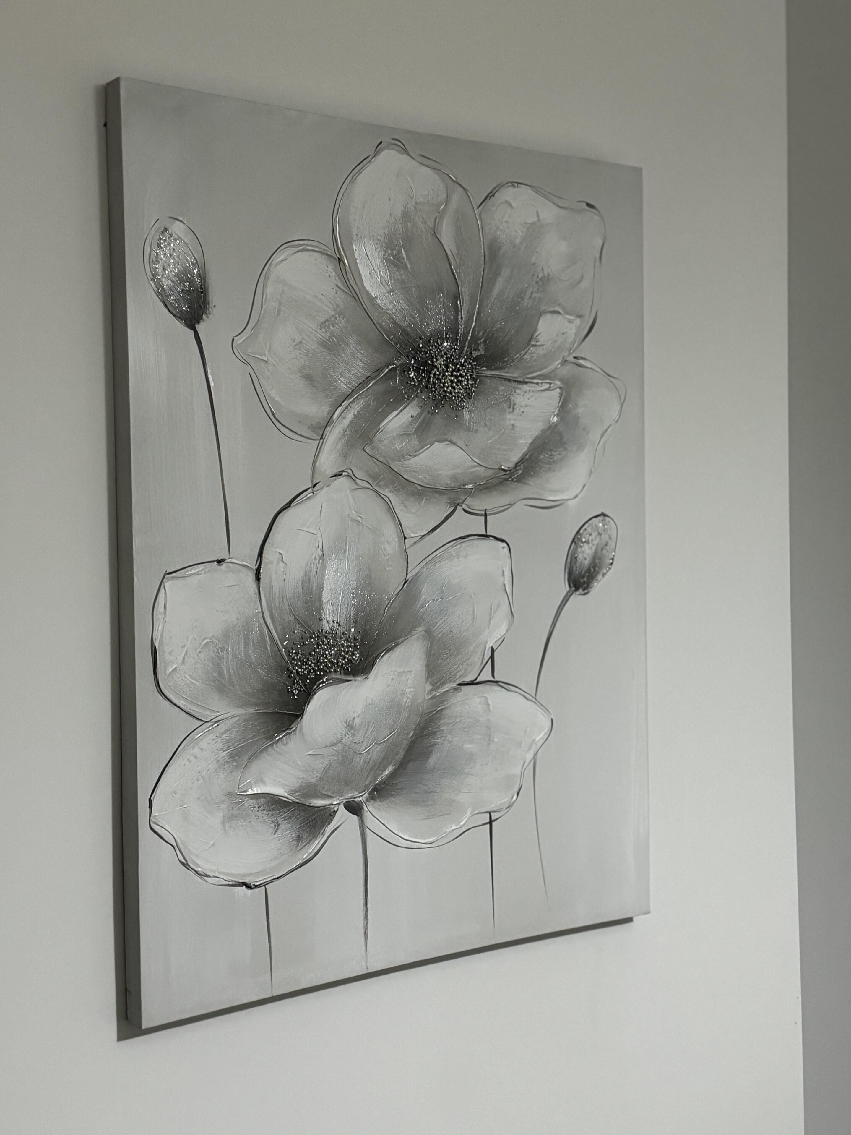 A grayscale painting of three flowers on a wall.