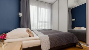 A bedroom with a bed, bedside table, and a mirror.