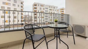 A balcony with two chairs and a small table, overlooking a residential building.