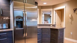 Una cocina moderna con un refrigerador de acero inoxidable, gabinetes de madera oscura y un dispensador de agua integrado.