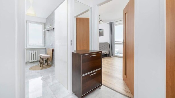 A modern, well-lit room with a wooden wardrobe, a small stool, and a radiator.