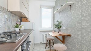 A modern kitchen with a gas stove, white cabinets, a patterned backsplash, and a window.