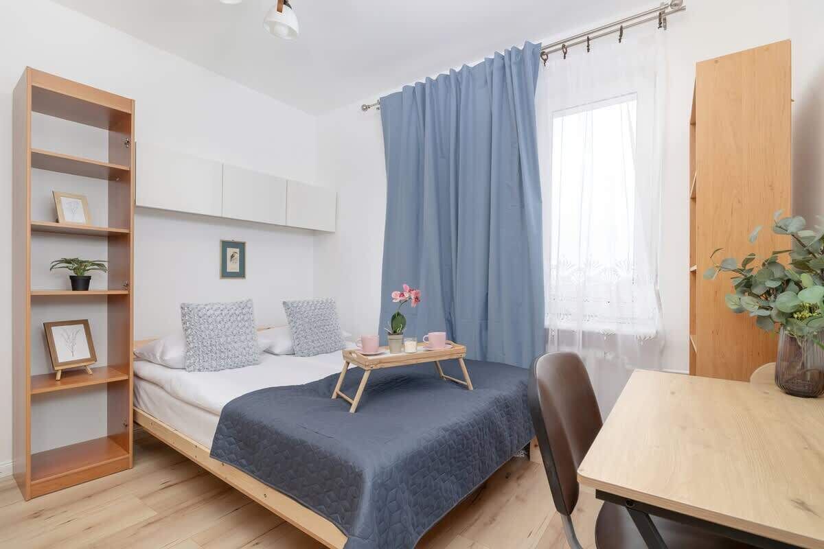 Een slaapkamer met een bed, een houten boekenkast, een bureau en een raam met gordijnen.