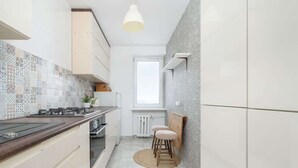 A modern kitchen with a patterned backsplash, white cabinetry, a wooden countertop, and a round rug.