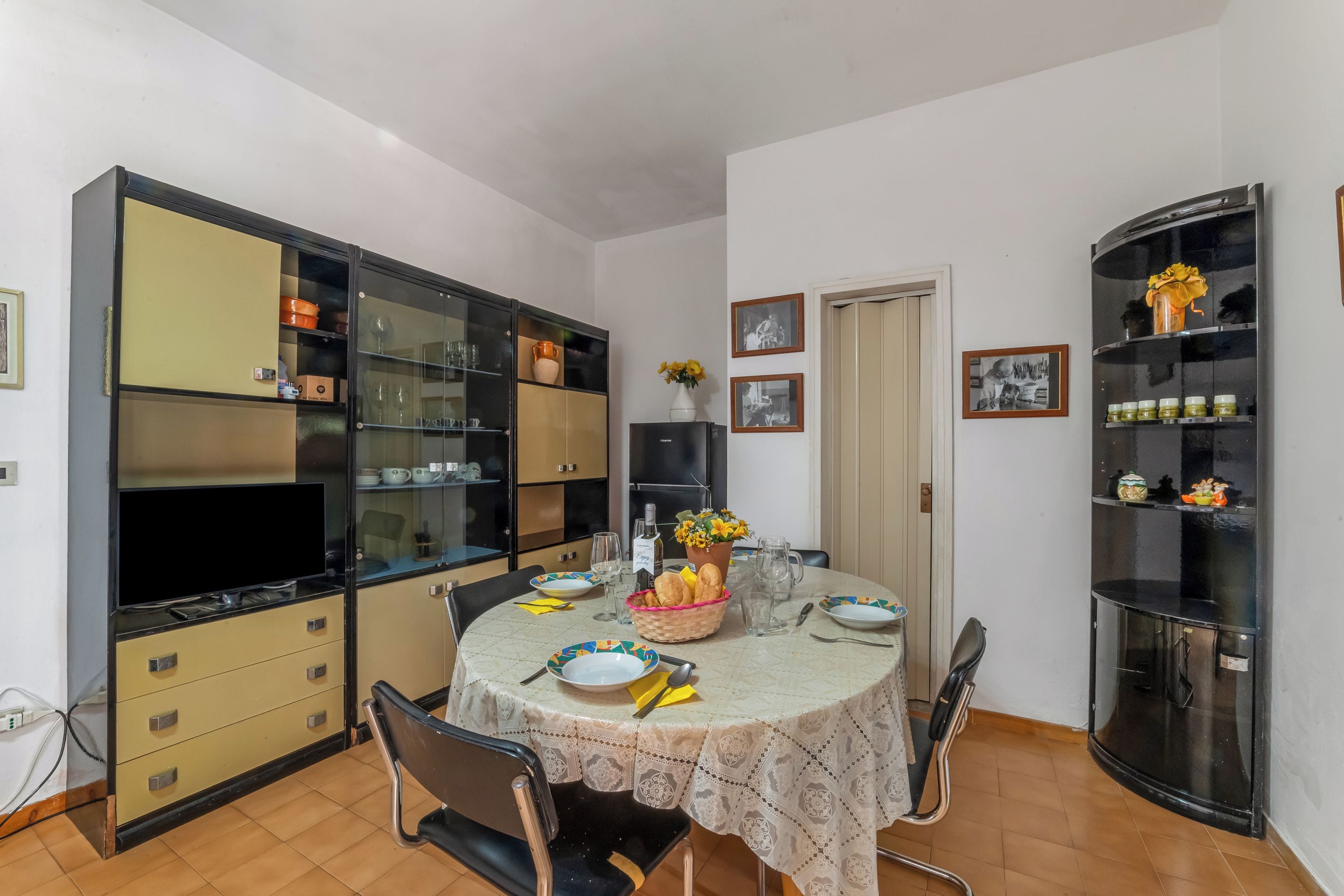 A dining area with a table set for four, surrounded by cabinets and shelves.