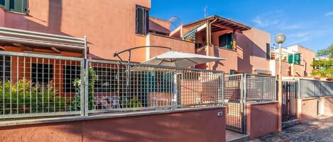 A residential building with a gated entrance, a balcony, and a clear blue sky.