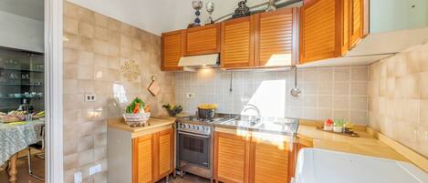A kitchen with wooden cabinets, a stainless steel oven, and a sink.