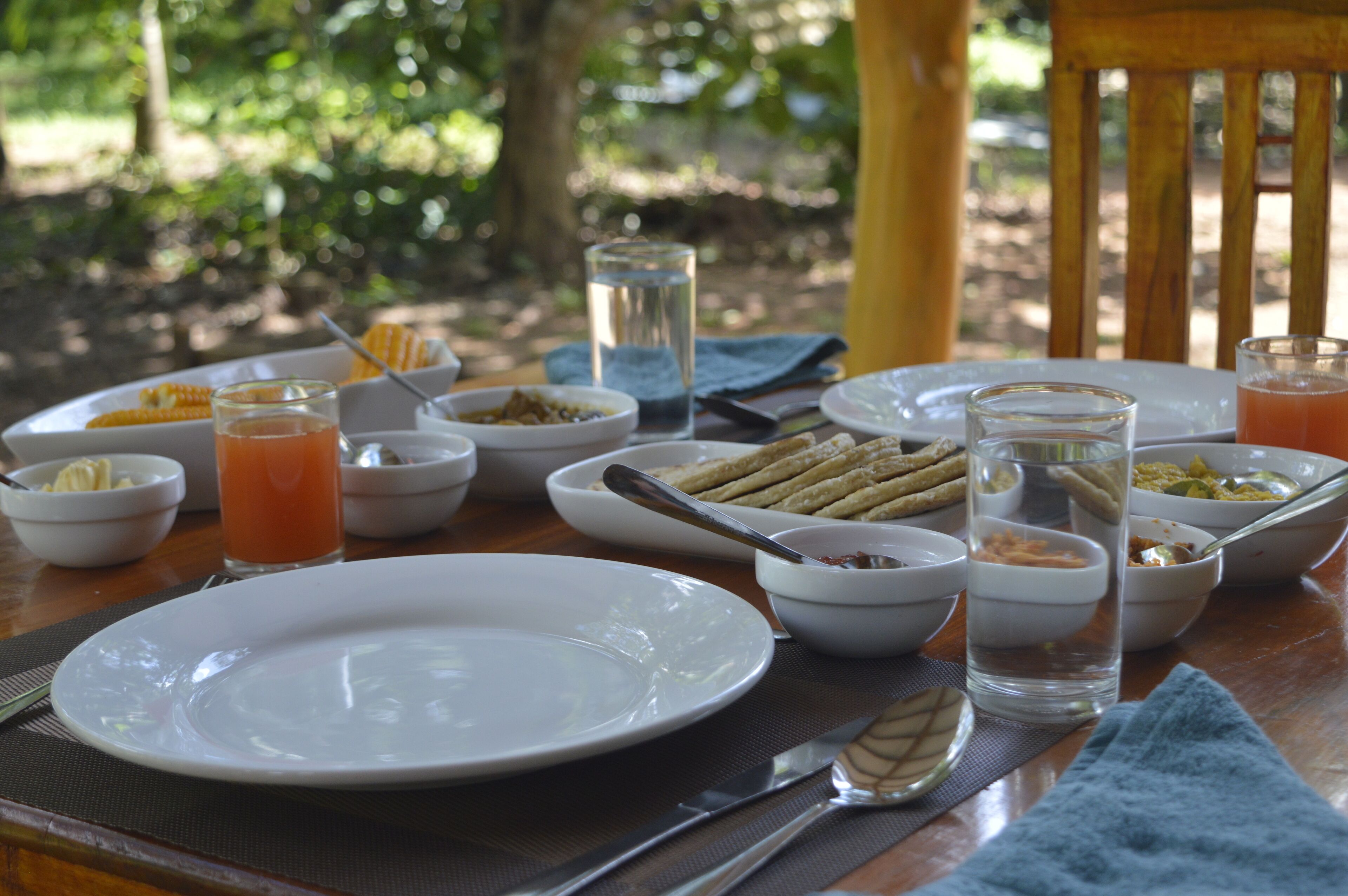 A dining table set outdoors with various dishes, glasses, and utensils.