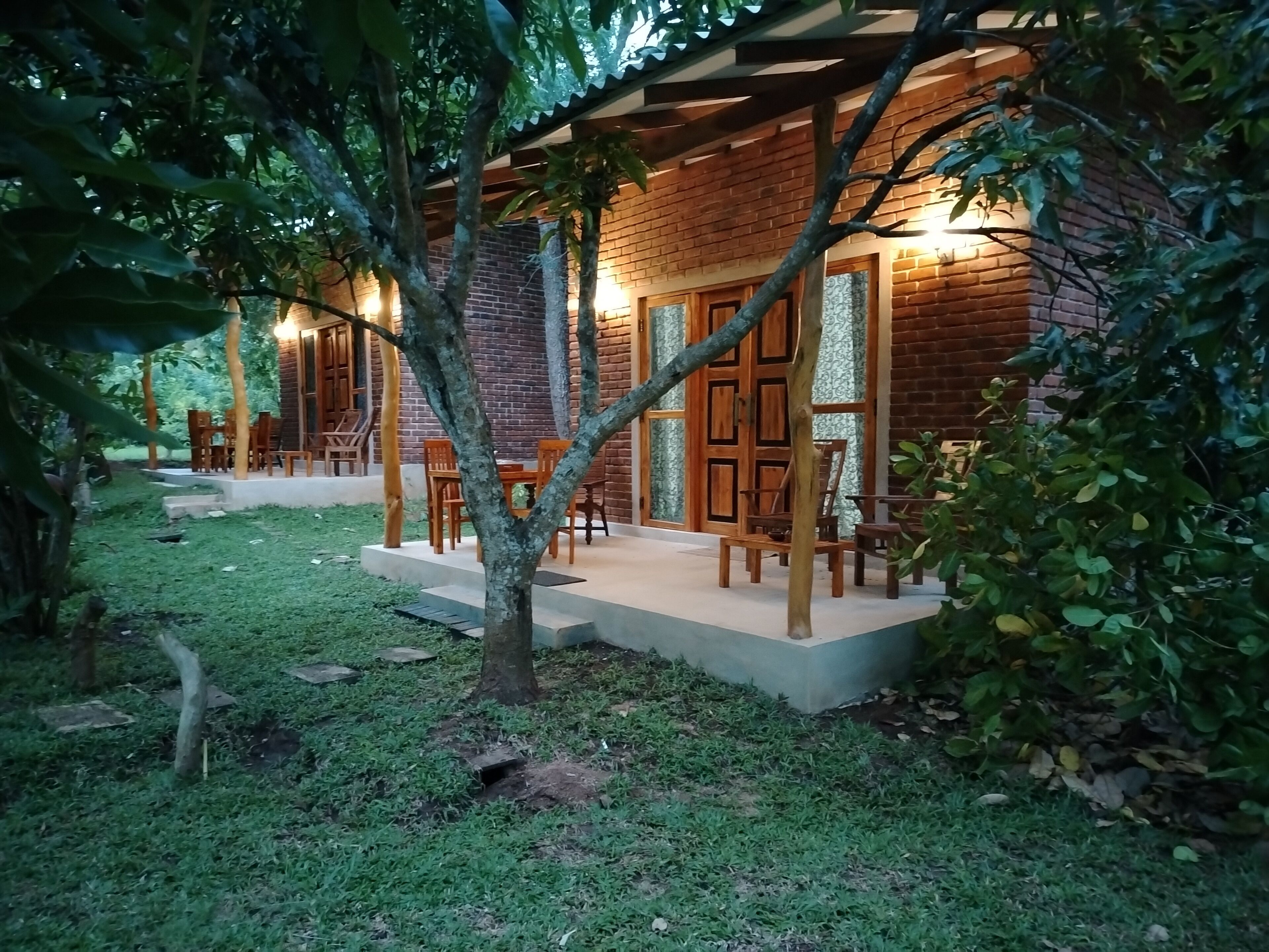 A rustic wooden building with a brick exterior, surrounded by a well-maintained garden and outdoor seating area.