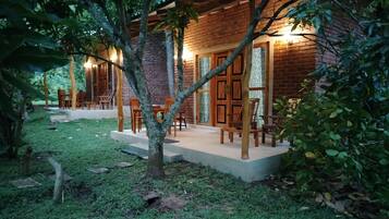 A rustic wooden building with a brick exterior, surrounded by a well-maintained garden and outdoor seating area.