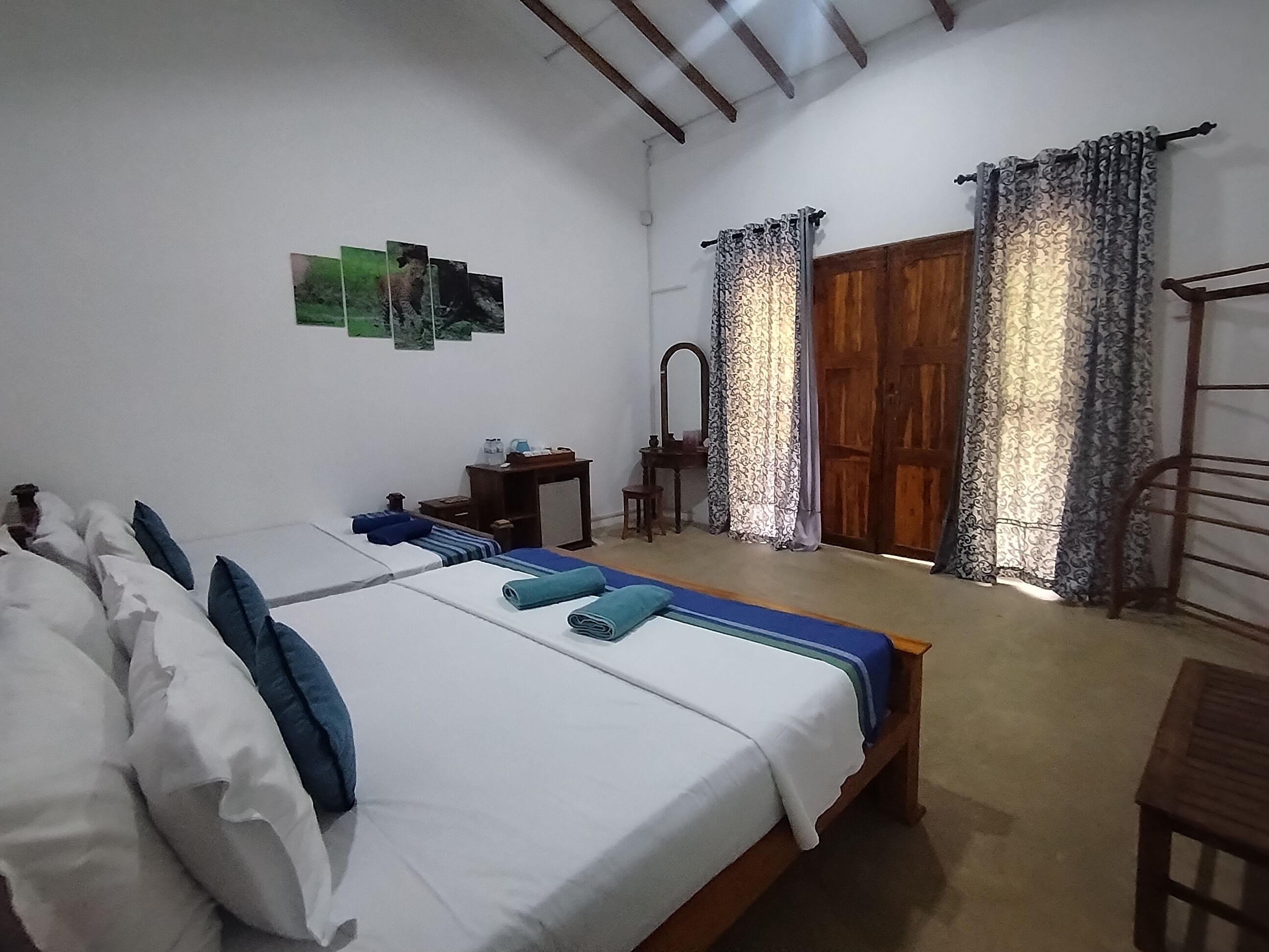 A bedroom with a bed, a small table, a mirror, and a wardrobe.