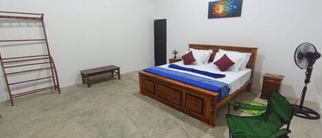 Een slaapkamer met een houten bed, een bankje, een ventilator en een trap.