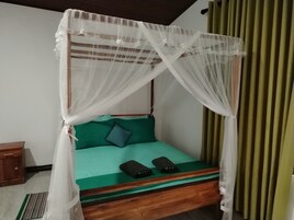 Una cama con dosel, ropa de cama verde y dos controles remotos sobre la cama.