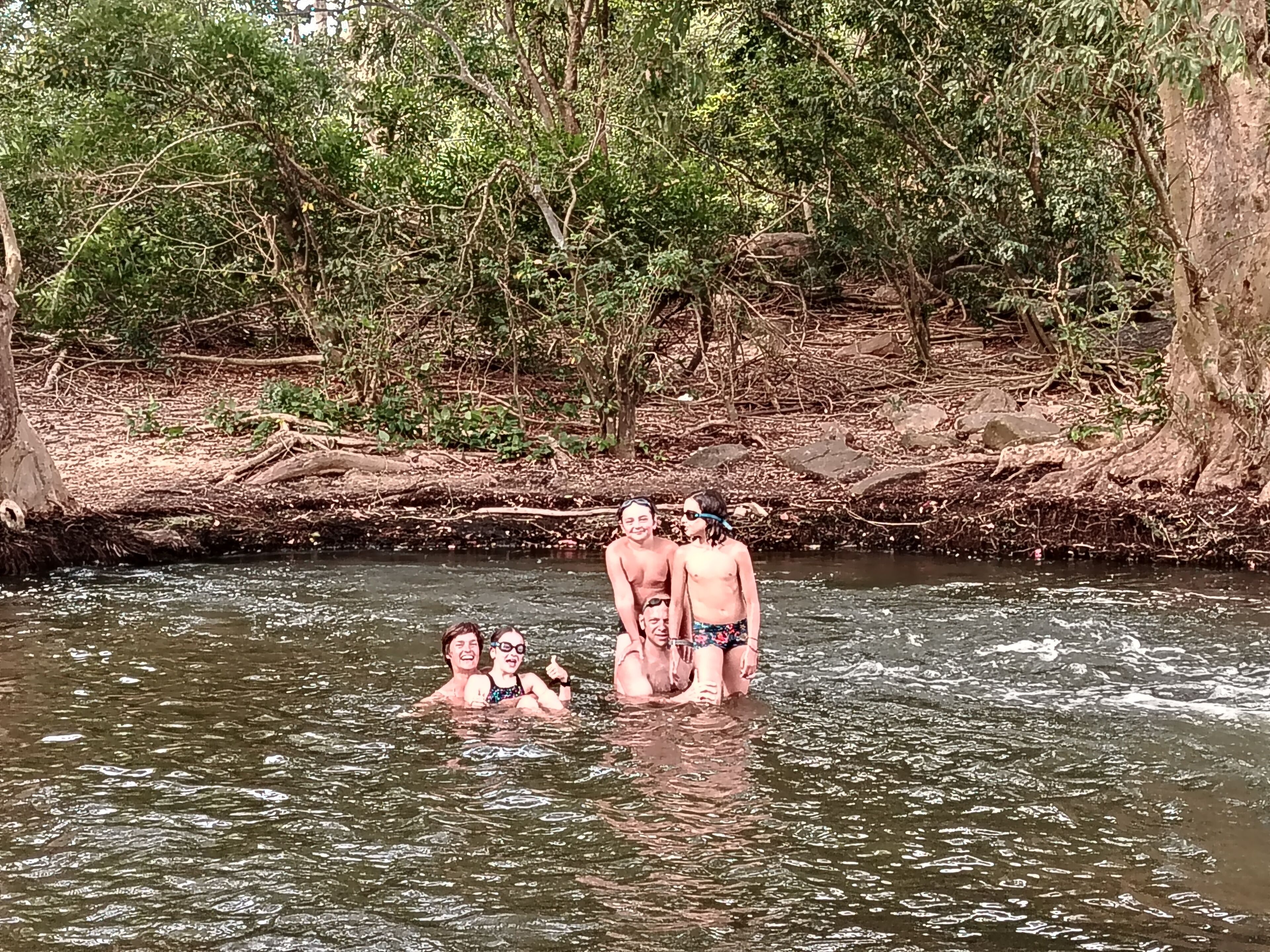 A group of people standing in a river surrounded by dense greenery.